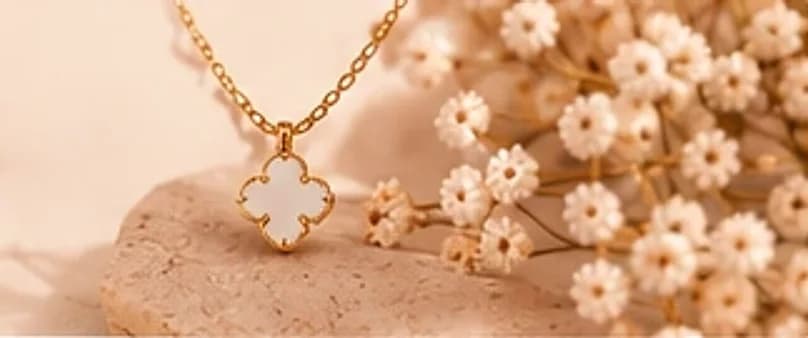 Gold clover necklace among baby’s breath flowers